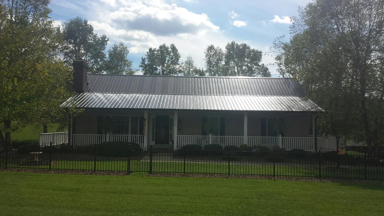 Gray metal roof on a brick ranch with a full width front porch — Gutter Guard Installation work by our crew in Riley